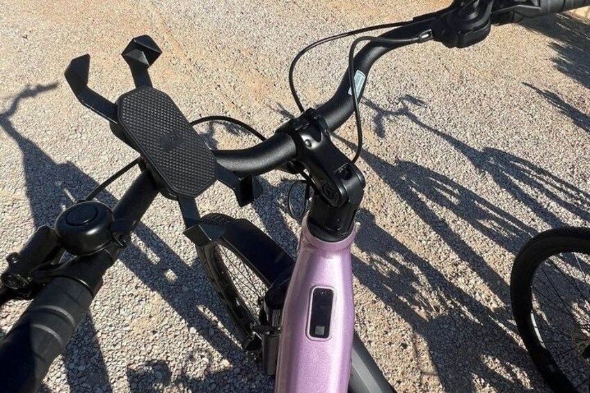 A bicycle with a purple frame and black handlebars, parked on a gravel surface. 4
