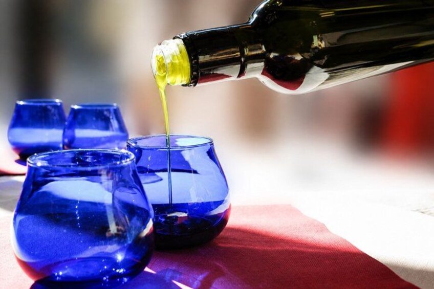 A bottle pouring a yellow liquid into a blue glass. 3