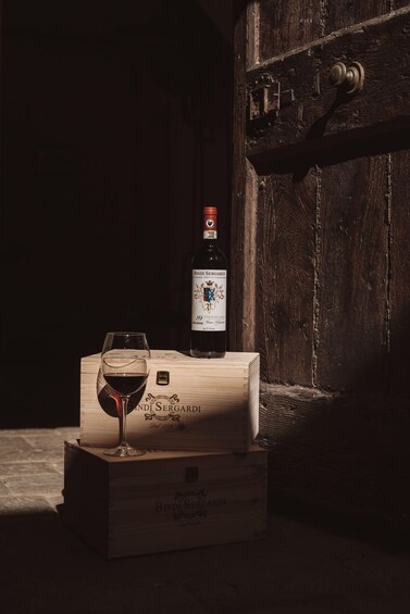 Eine Weinflasche und ein Glas auf einer Holzkiste mit dem Text 'Bindi Sergardi' und '89 Chianti Classico'. 5