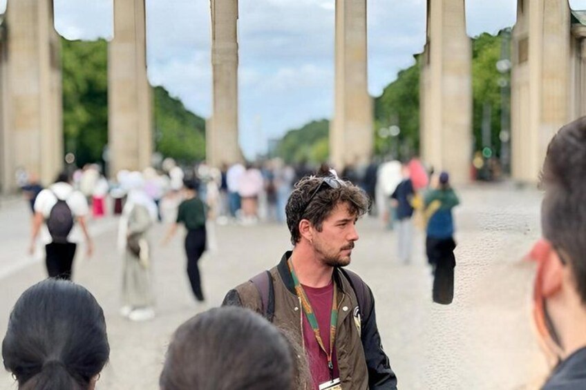 A person standing in a crowd with large stone columns in the background. 1