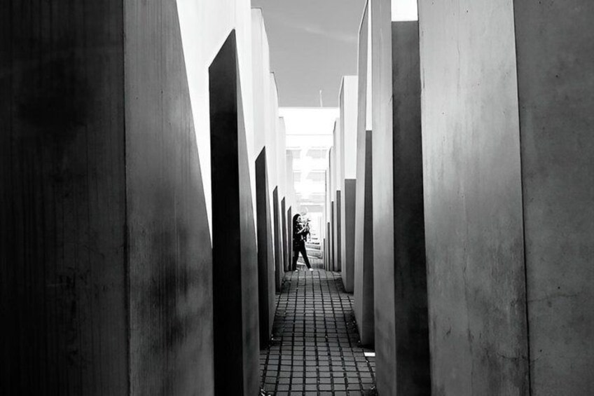 A person walking down a corridor lined with tall concrete pillars. 5