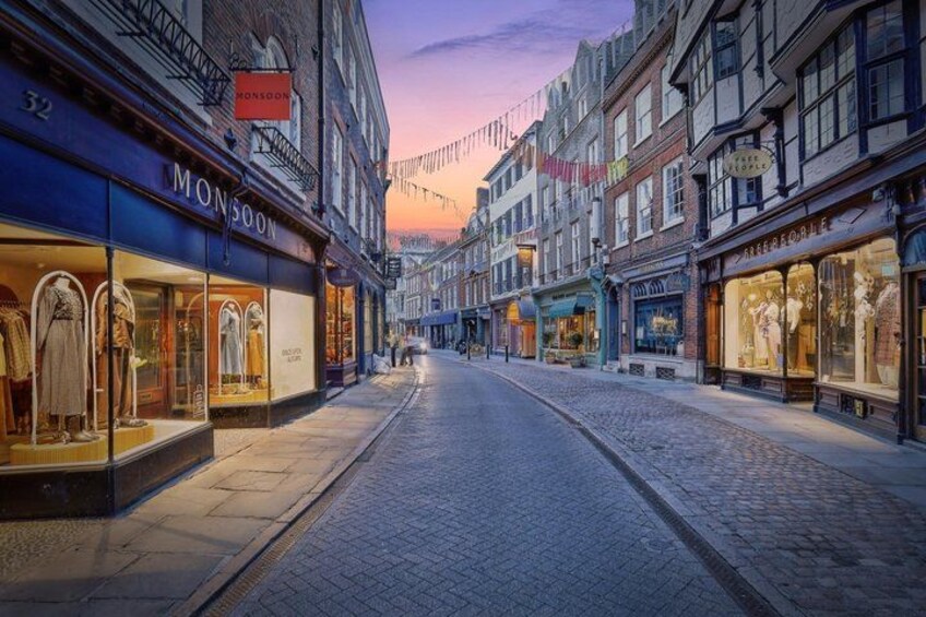 A cobblestone street lined with shops, including a visible store named 'Monsoon'. 3