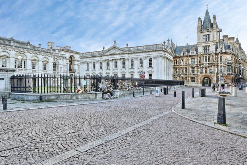 A cobblestone square with historic buildings, a fountain, and a statue. 4
