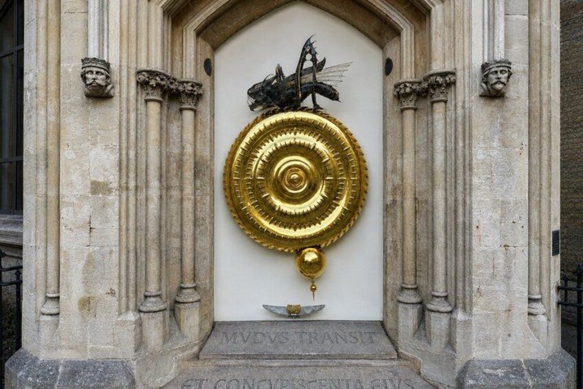 A building entrance with a golden door knocker, stone columns, and a plaque with inscriptions. 2