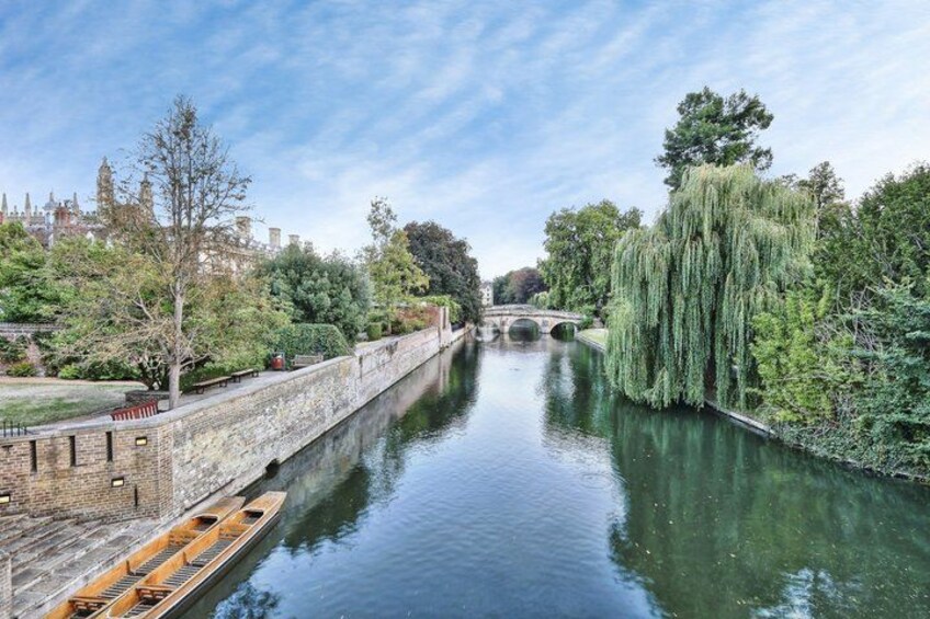 A river with a bridge, trees, and a rowboat. 5