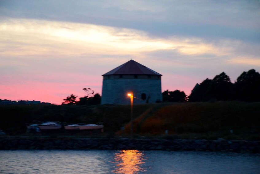 Ein Turm an einem Gewässer im Dämmerlicht, der Himmel ist rosa. 5