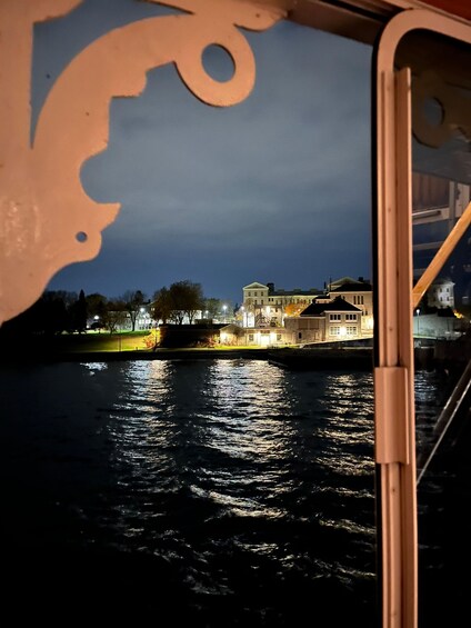 Ein Fluss mit Spiegelungen von Lichtern, ein beleuchtetes Gebäude und eine Brücke. 4