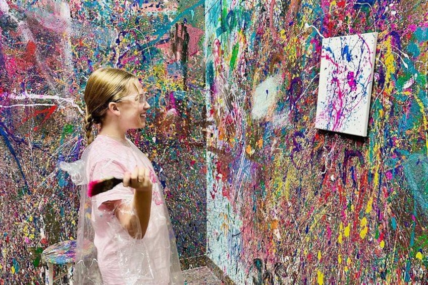 A person in a plastic bag painting on a wall with a variety of colors. 5