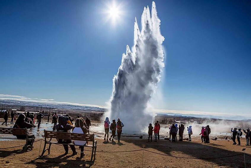 A geyser erupting with people observing. 5