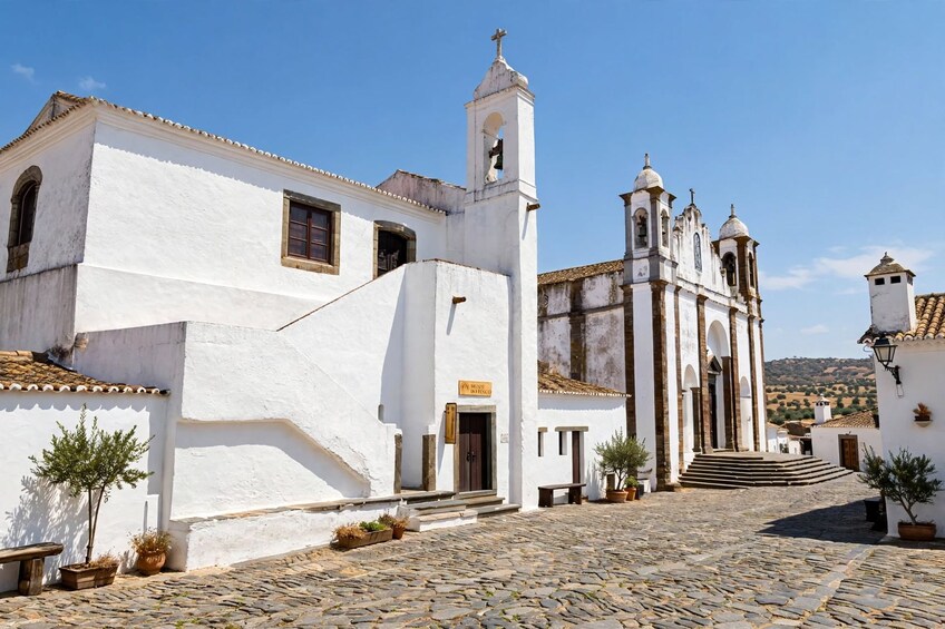 A white church with a bell tower and a cobblestone street. 3