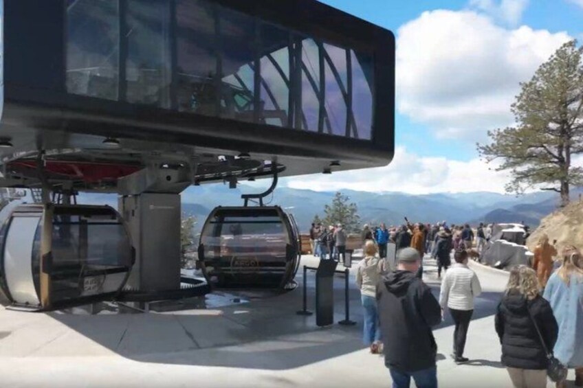 A ski lift with people waiting and a mountainous landscape in the background. 3