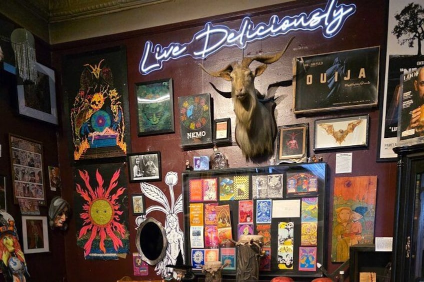 A wall with various posters, a neon sign, and a mounted animal head. 3