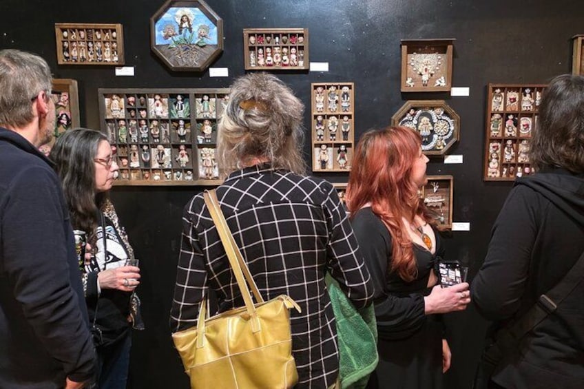 People viewing a collection of framed items on display. 4