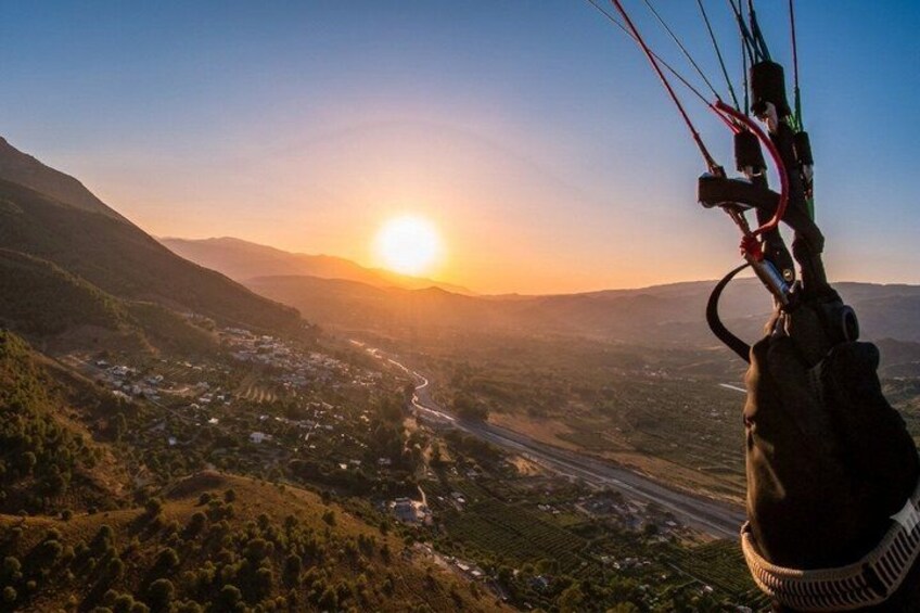A landscape with a sun setting behind hills, a road, and a kite in the foreground. 4