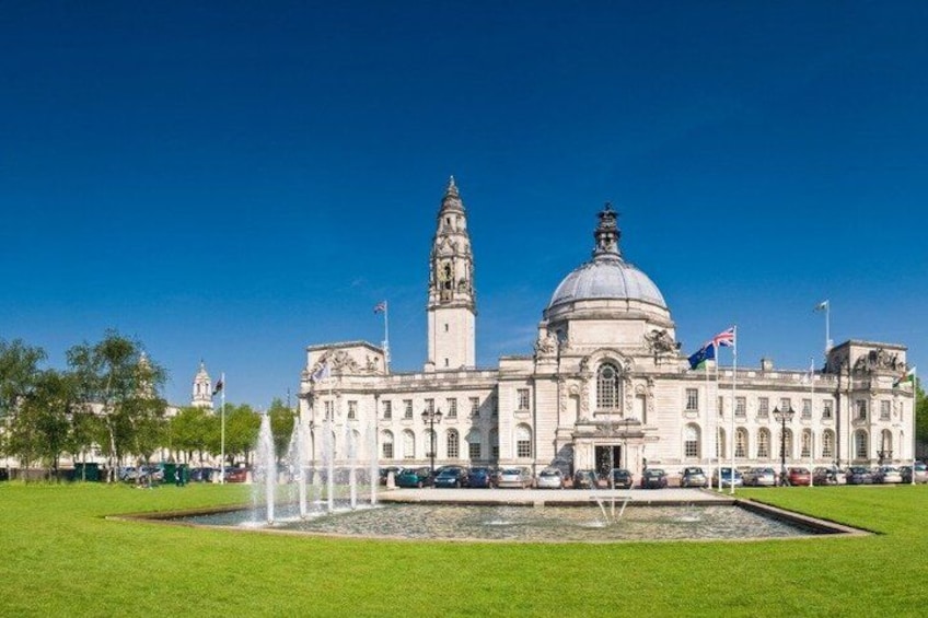 A large historic building with a prominent tower and dome, surrounded by a well-maintained lawn and a fountain. 4