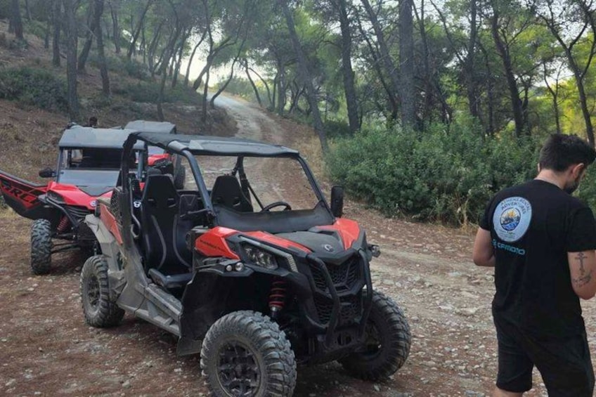 A red and black off-road vehicle on a dirt path in a forested area. 4