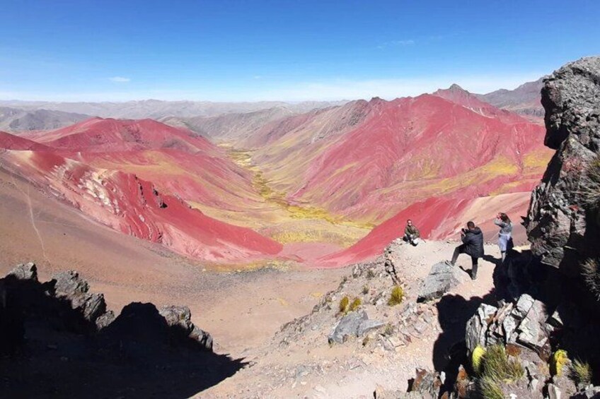 A mountainous landscape with red and yellow hues, rocky terrain, and a clear sky. 2
