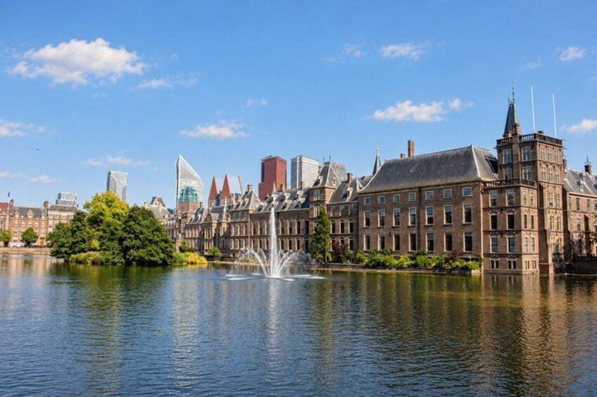 A historic building with a fountain in front, a body of water, and modern skyscrapers in the background. 3