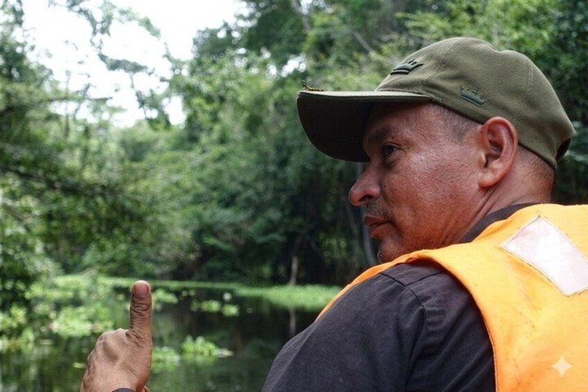 A person pointing towards a body of water surrounded by dense greenery. 3