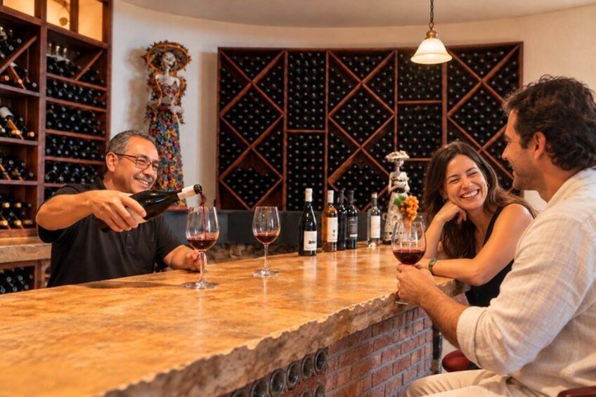 A wine tasting event with a wooden counter, wine bottles, and a decorative sculpture in the background. 1