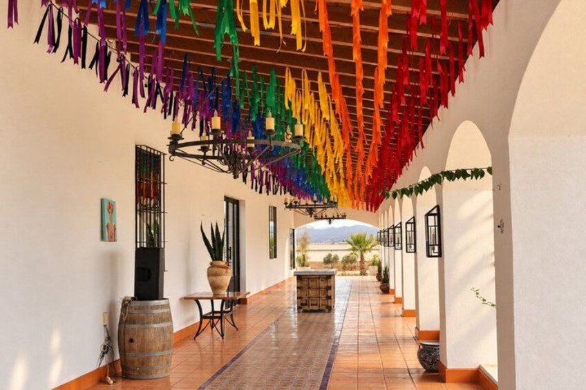 A corridor with colorful ribbons hanging from the ceiling, a tiled floor, and arched doorways. 3