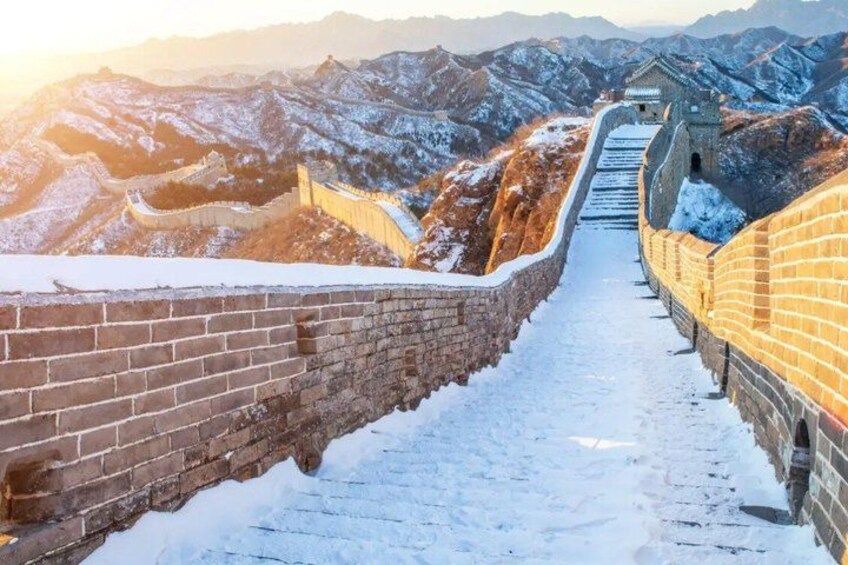 A snow-covered path along the Great Wall of China, with mountainous terrain in the background. 4
