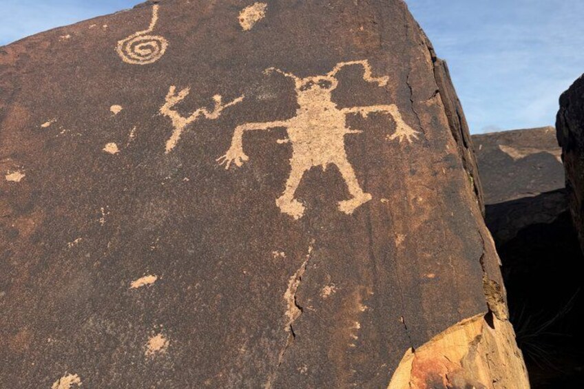 A large rock with ancient petroglyphs including a humanoid figure and spiral designs. 4