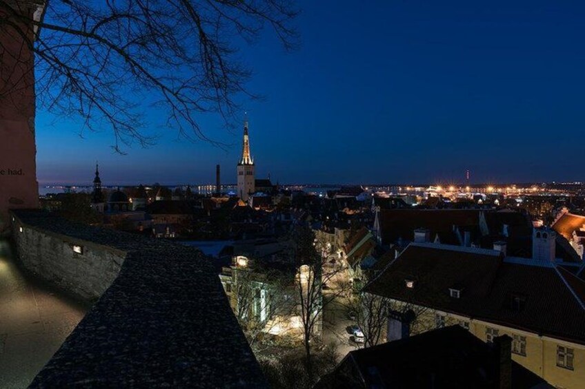 A cityscape at dusk with a prominent church spire, illuminated buildings, and a cobblestone pathway. 5