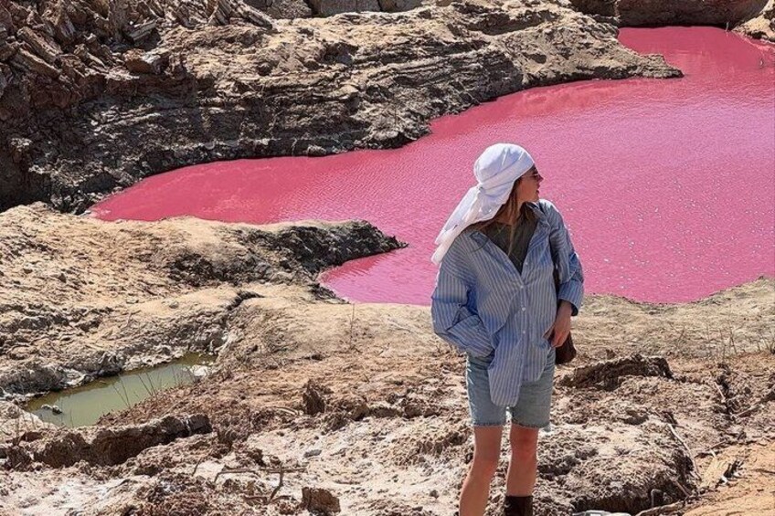 A person standing on rocky terrain with a red pool in the background. 3