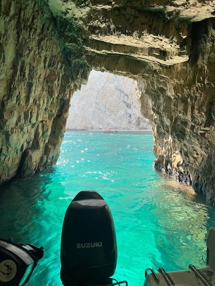 A boat with a Suzuki motor in a turquoise sea, entering a rocky cave. 2
