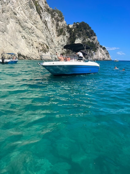 A boat anchored near a rocky coastline with clear turquoise water. 5