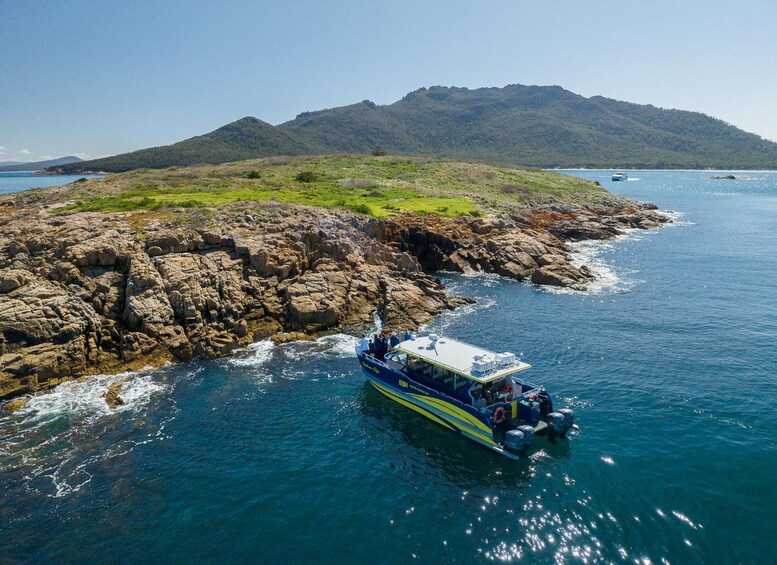 Ein Boot fährt an felsigen Ufern entlang, mit einer Berglandschaft im Hintergrund. 5