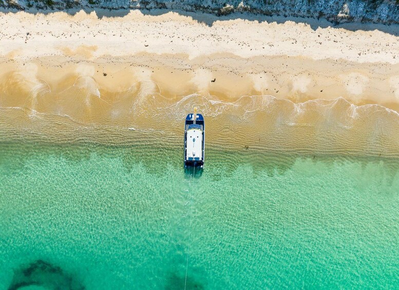 Ein Boot liegt in klarem, türkisblauem Wasser vor einem Sandstrand. 4