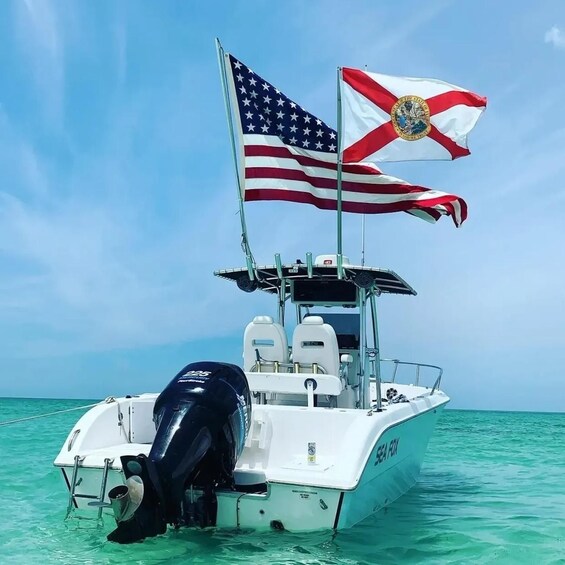 A white boat with American and state flags, floating on clear turquoise water. 1