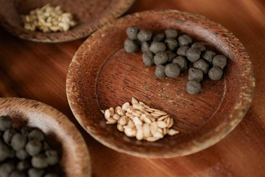 Three wooden bowls containing different types of seeds on a wooden surface. 3
