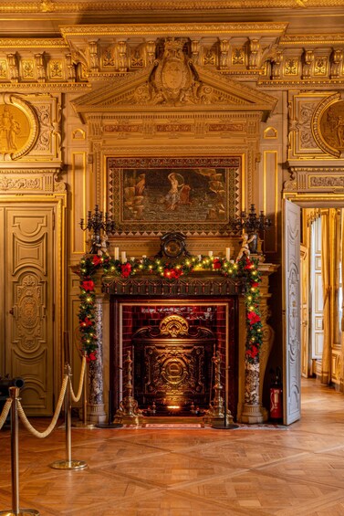 An ornate room with a fireplace, gold decorations, and a Christmas tree. 2