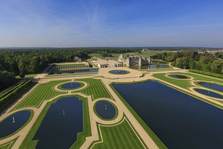 A grand estate with symmetrical gardens, multiple water bodies, and a large central building. 1