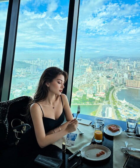 A person dining at a table with a cityscape view. 2
