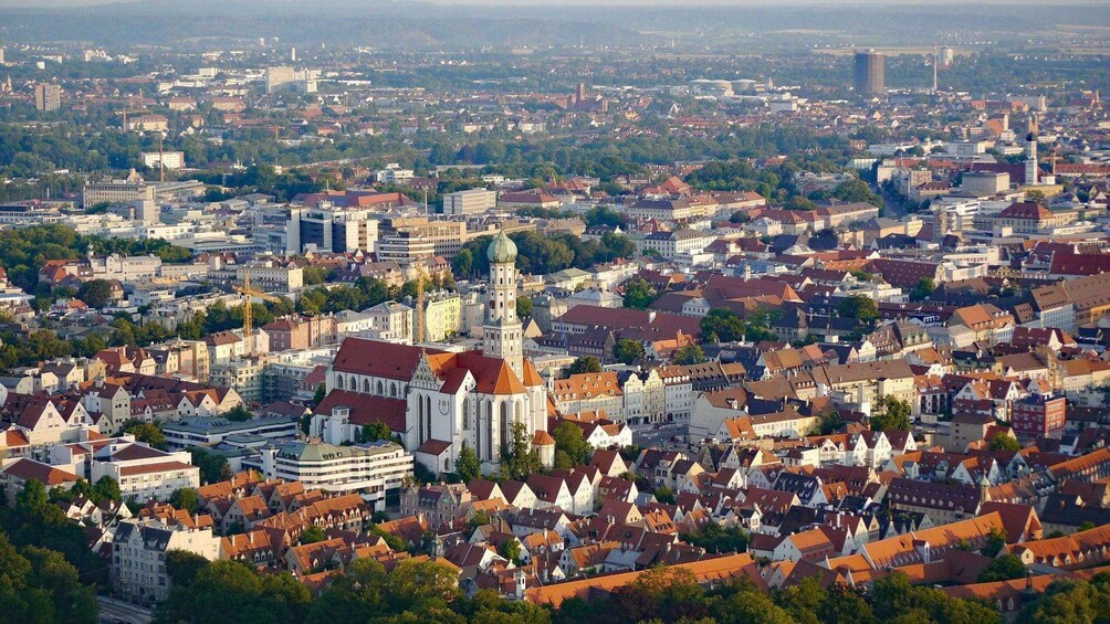 Una vista panorámica de una ciudad con arquitectura histórica, que incluye una iglesia destacada con una aguja alta y una catedral con cúpula. 4