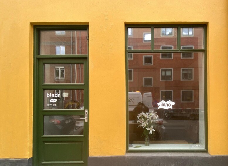 Une porte verte avec une fenêtre, un mur jaune et le reflet d’un immeuble doté de fenêtres. 4