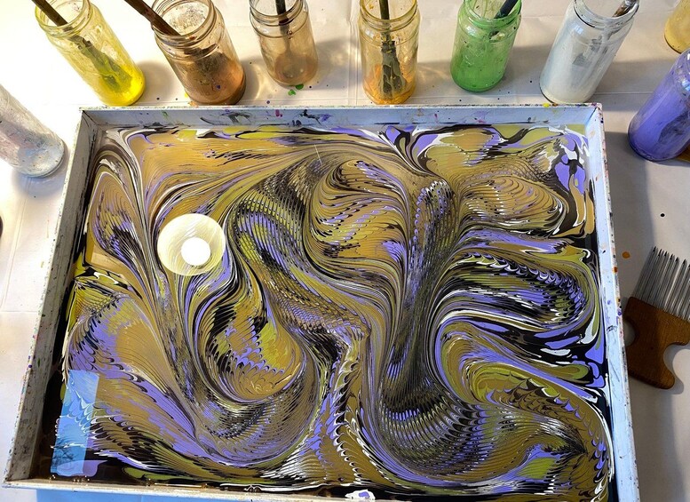 Un plateau contenant des pots de peinture aux couleurs variées, avec un effet marbré, et un couteau à palette. 3