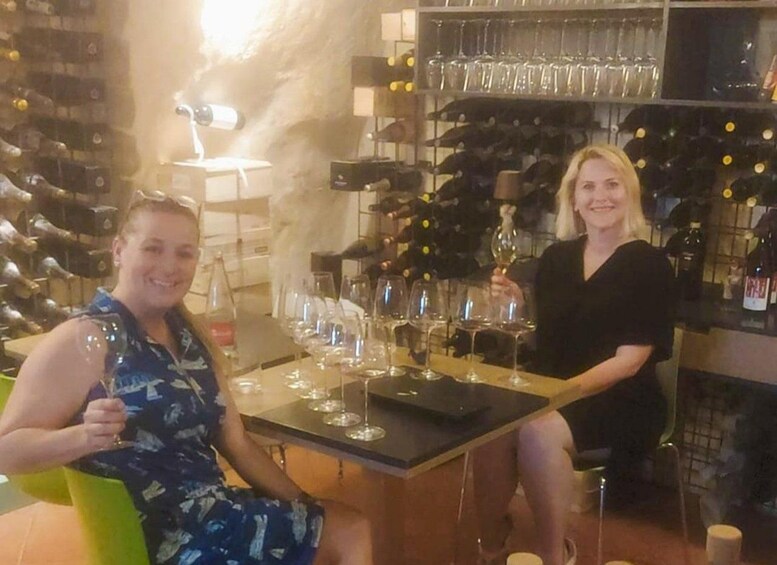 Two people seated at a table with wine glasses and bottles in a bar setting. 3