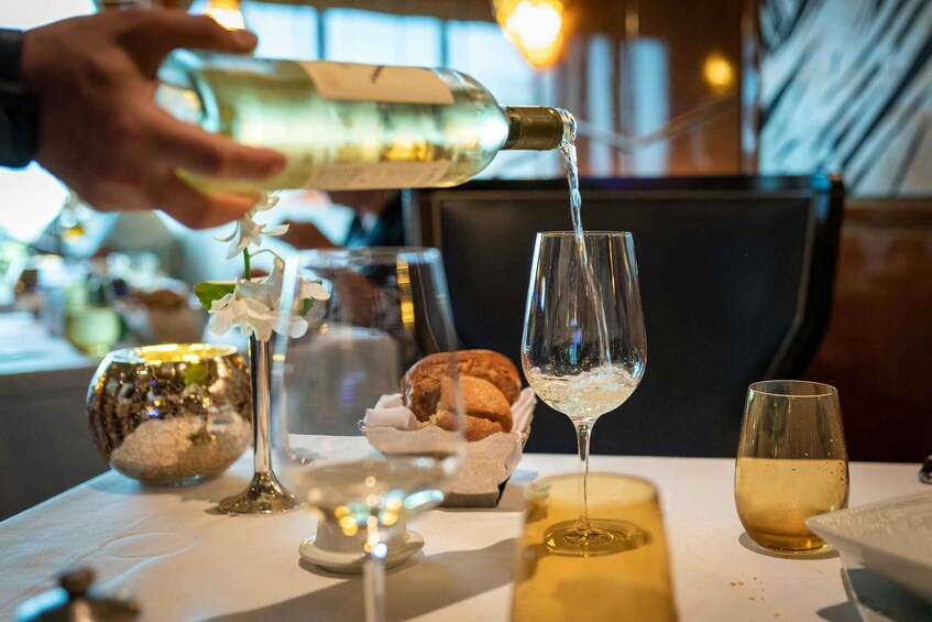 A person pouring a clear liquid into a tall glass. 4