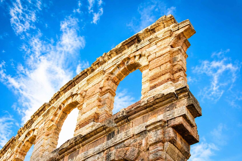 Un antiguo arco de piedra con intrincados grabados, frente a un cielo azul claro con nubes dispersas. 2