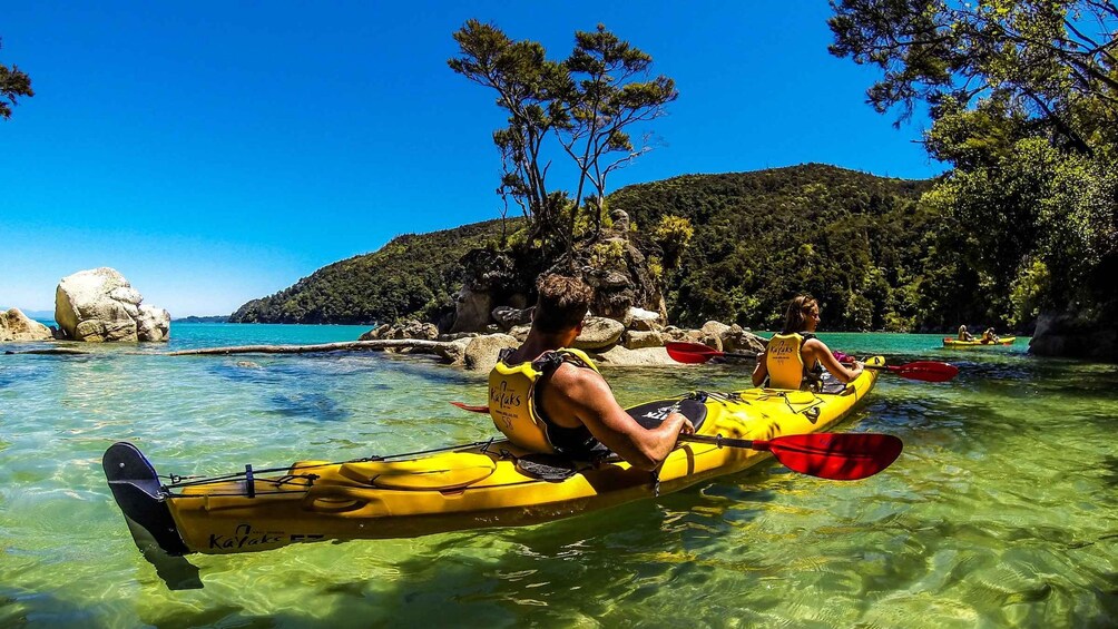 Una persona practica kayak en aguas turquesas cristalinas, con montañas al fondo. 3