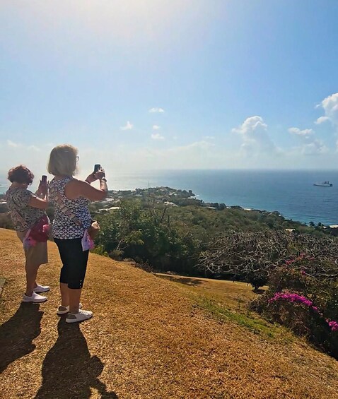 Dos personas fotografiando un paisaje costero con un barco a lo lejos. 2