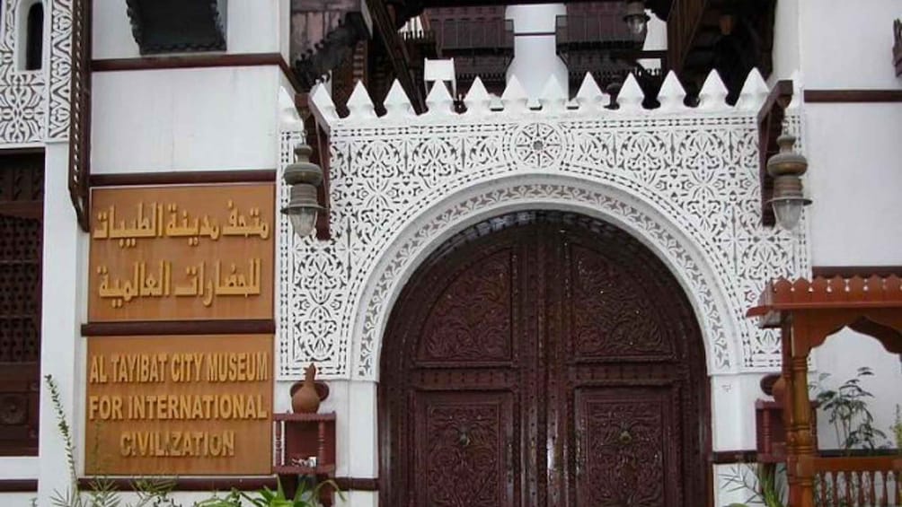 Un edificio tradicional con intrincados trabajos de celosía blanca y una puerta de madera grande. 1