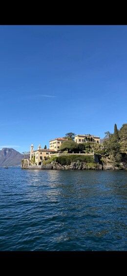Una villa costera con una torre, rodeada de vegetación exuberante y un cielo azul despejado. 3