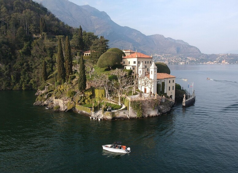 Una finca junto al lago con un edificio blanco, un bote en el agua y montañas al fondo. 1