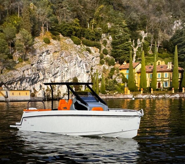 Un barco a motor en aguas tranquilas, con una costa rocosa y edificios coloridos al fondo. 5